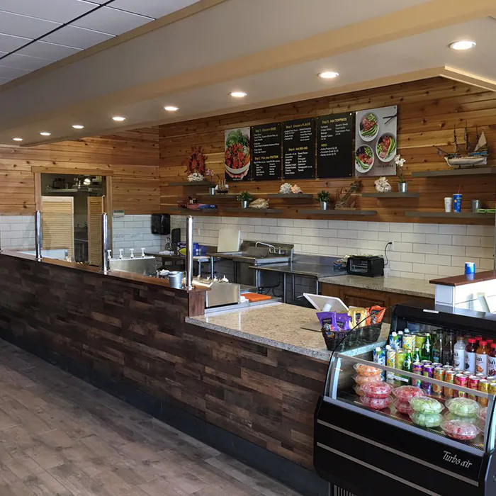 Full restaurant dining room with Poke Makana branding, light wood furniture, and stone accent walls at Poke Makana, a Hawaiian restaurant in Sherwood